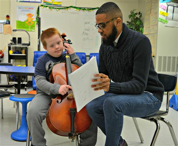 Brian Smalls helps Jake practice the cello 